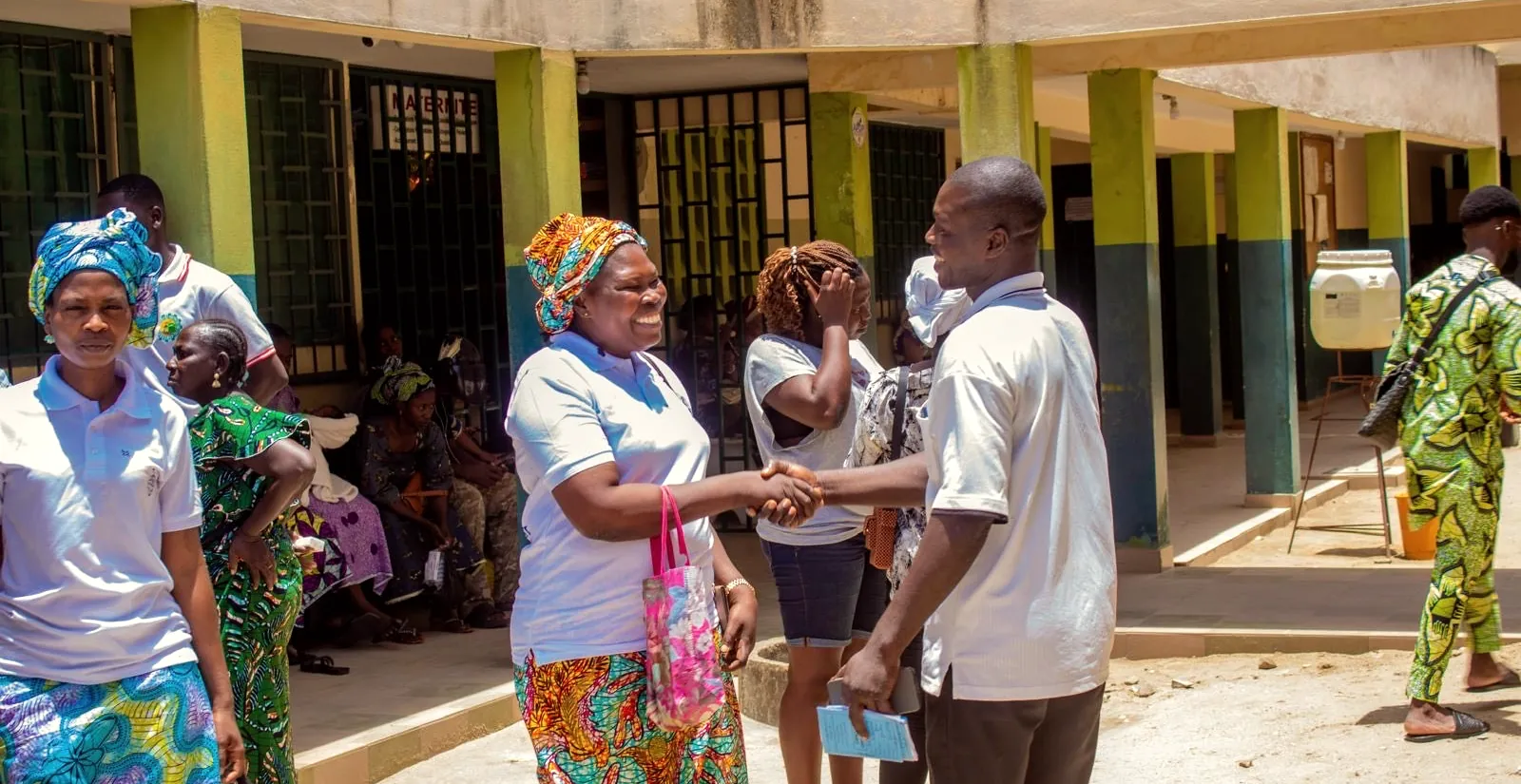 A volunteer shakes hands with a smiling woman outside the hospital